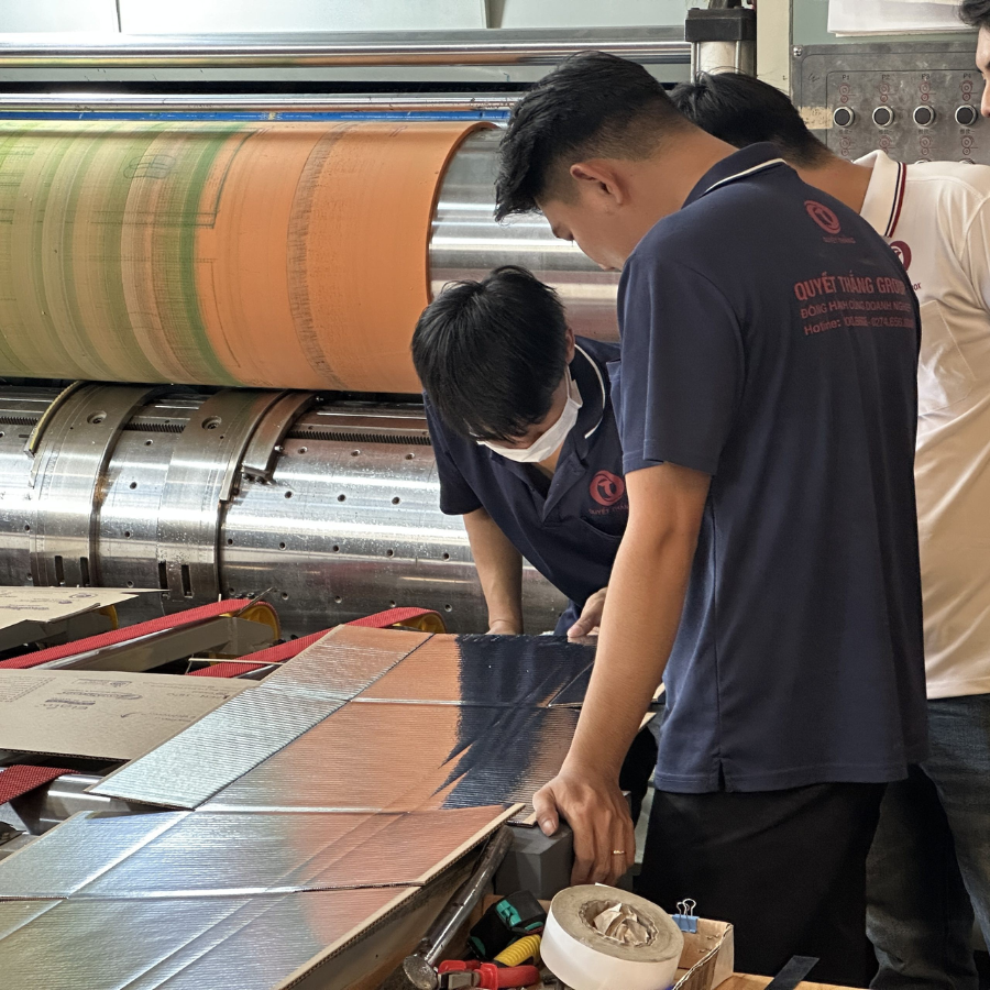 Kỹ thuật viên kiểm tra mẫu thùng carton trước sản xuất: đo kích thước, cắt mặt cắt ngang và đo chỉ số BCT.